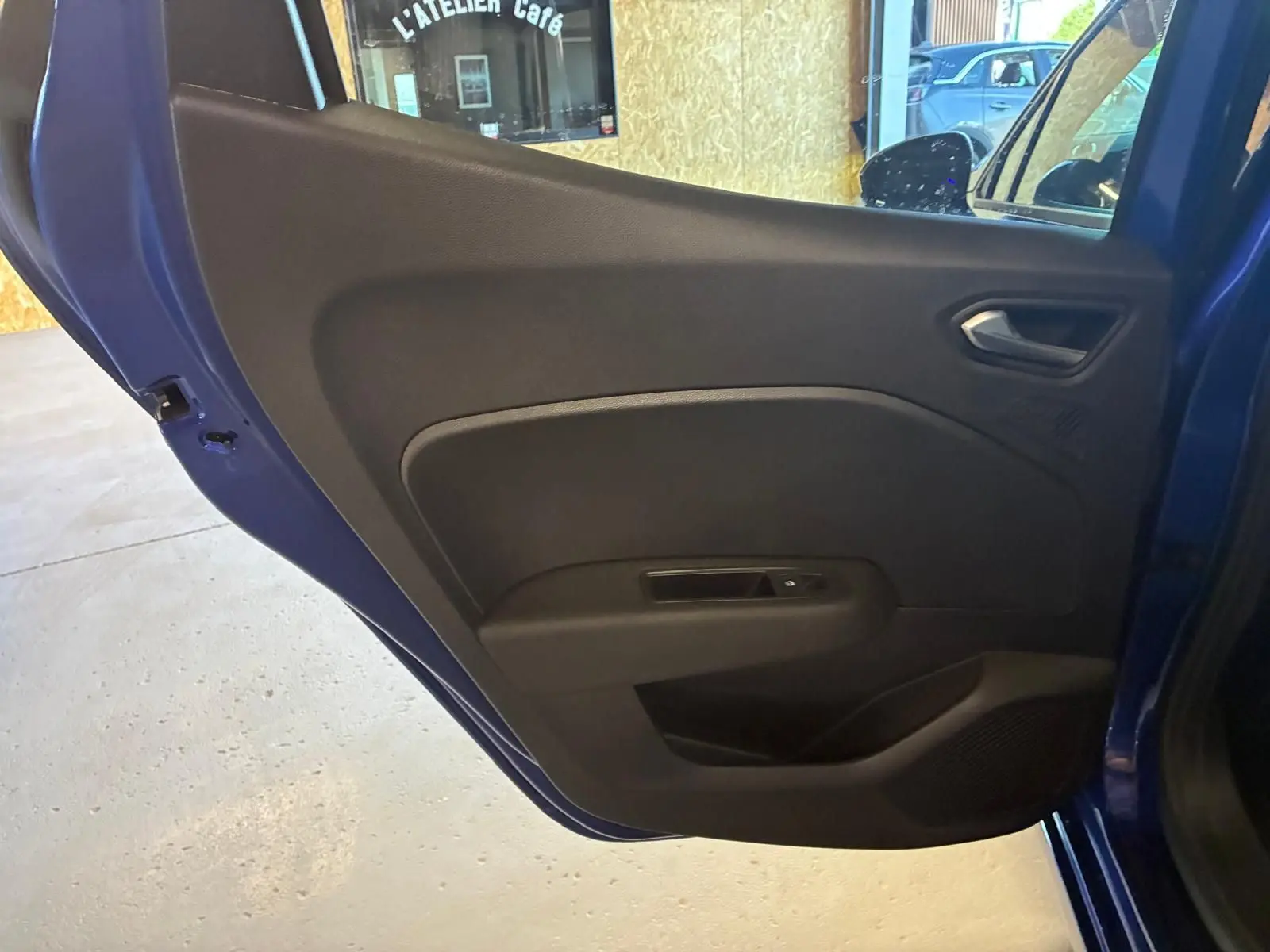 Vue intérieure de la porte arrière droite bleu iron de la Renault Clio V E-TECH 145 TECHNO avec habillage noir simple.
