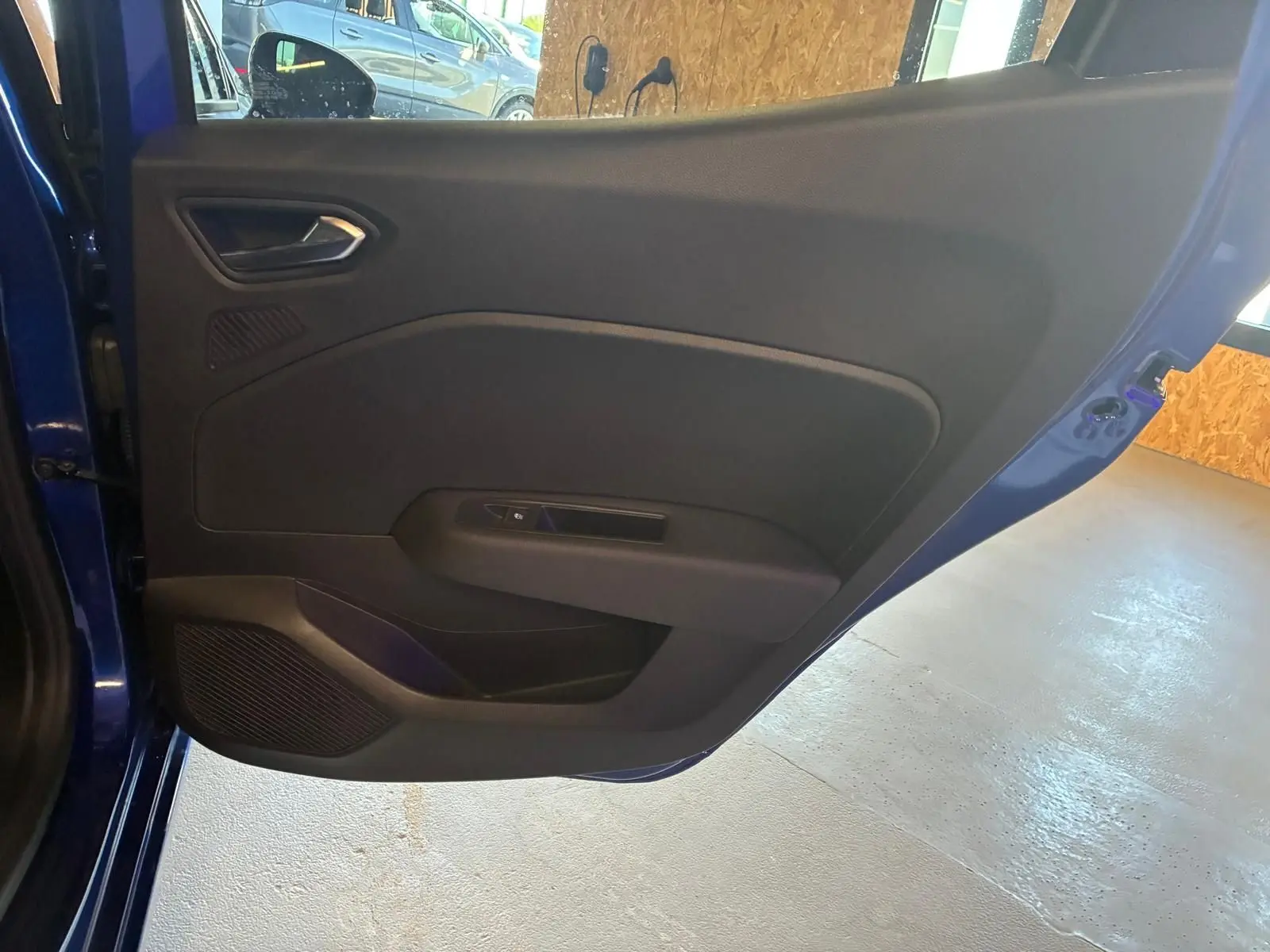 Vue rapprochée de la porte arrière gauche bleu iron d’une Renault Clio V E-Tech 145 Techno avec garniture intérieure noire.