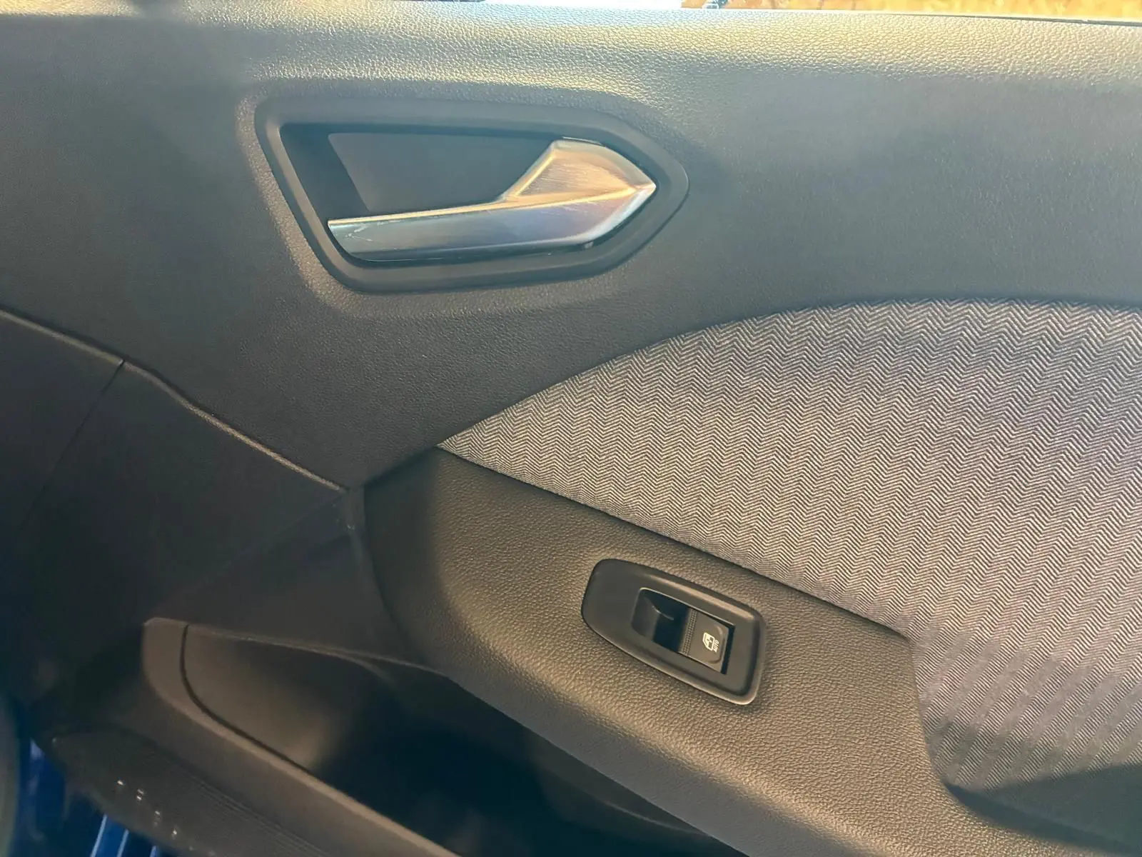 Détail de la porte intérieure côté gauche de la Renault Clio V E-TECH 145 TECHNO 2025 avec tissu gris et poignée argentée.