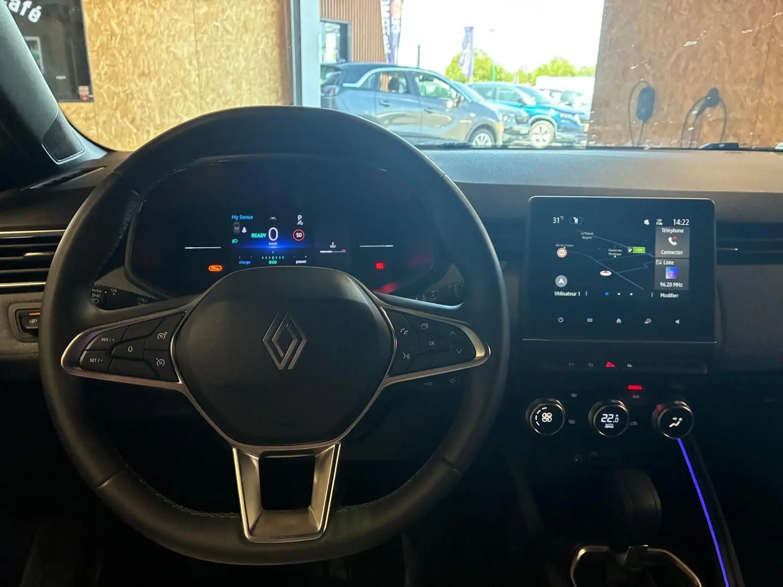 Vue intérieure centrée sur le volant Renault Clio V E-TECH 145 bleu Iron, avec tableau de bord numérique et écran tactile.