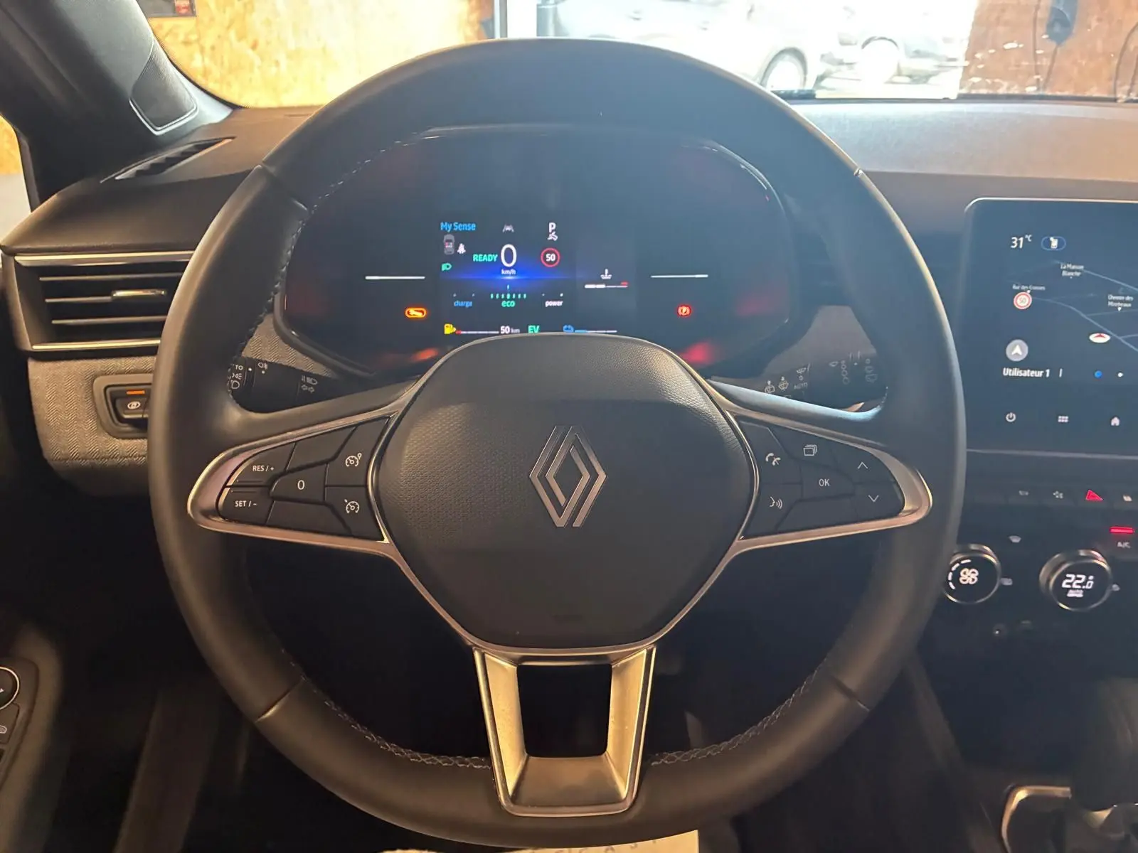 Vue centrée sur le volant noir de la Renault Clio V E-TECH 145 TECHNO 2025 avec tableau de bord numérique et écran tactile.