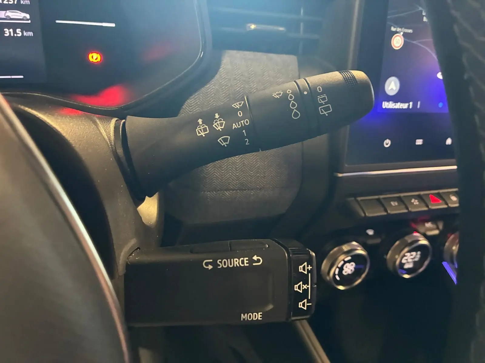 Vue rapprochée du commodo gauche et des commandes multimédia du tableau de bord d'une Renault Clio V E-TECH 145 Techno.
