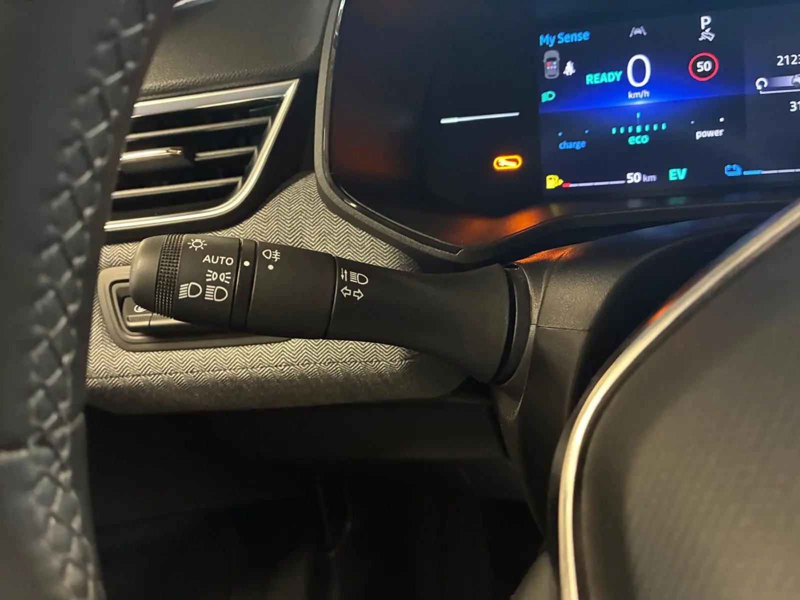 Gros plan sur la commande des phares et clignotants à gauche du volant dans le tableau de bord gris noir de la Renault Clio V E-Tech 145.