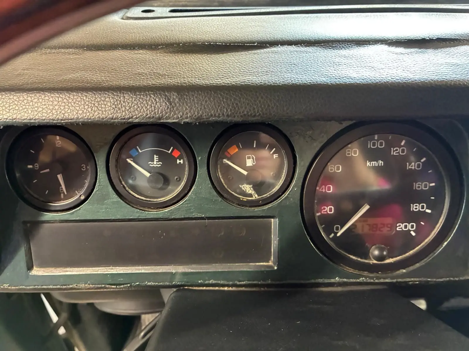 Gros plan sur le tableau de bord vert foncé du Land Rover Defender 110 2005, montrant les compteurs ronds et le compteur de vitesse.