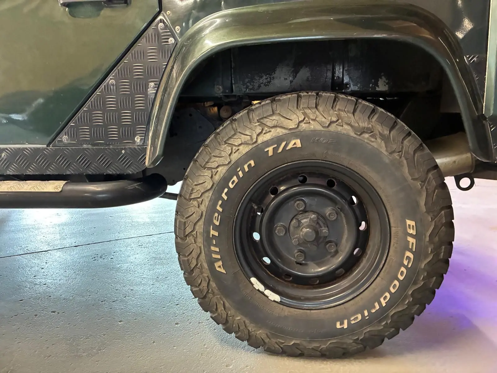 Gros plan sur la roue arrière droite d’un Land Rover Defender 110 vert avec pneu BFGoodrich tout-terrain.