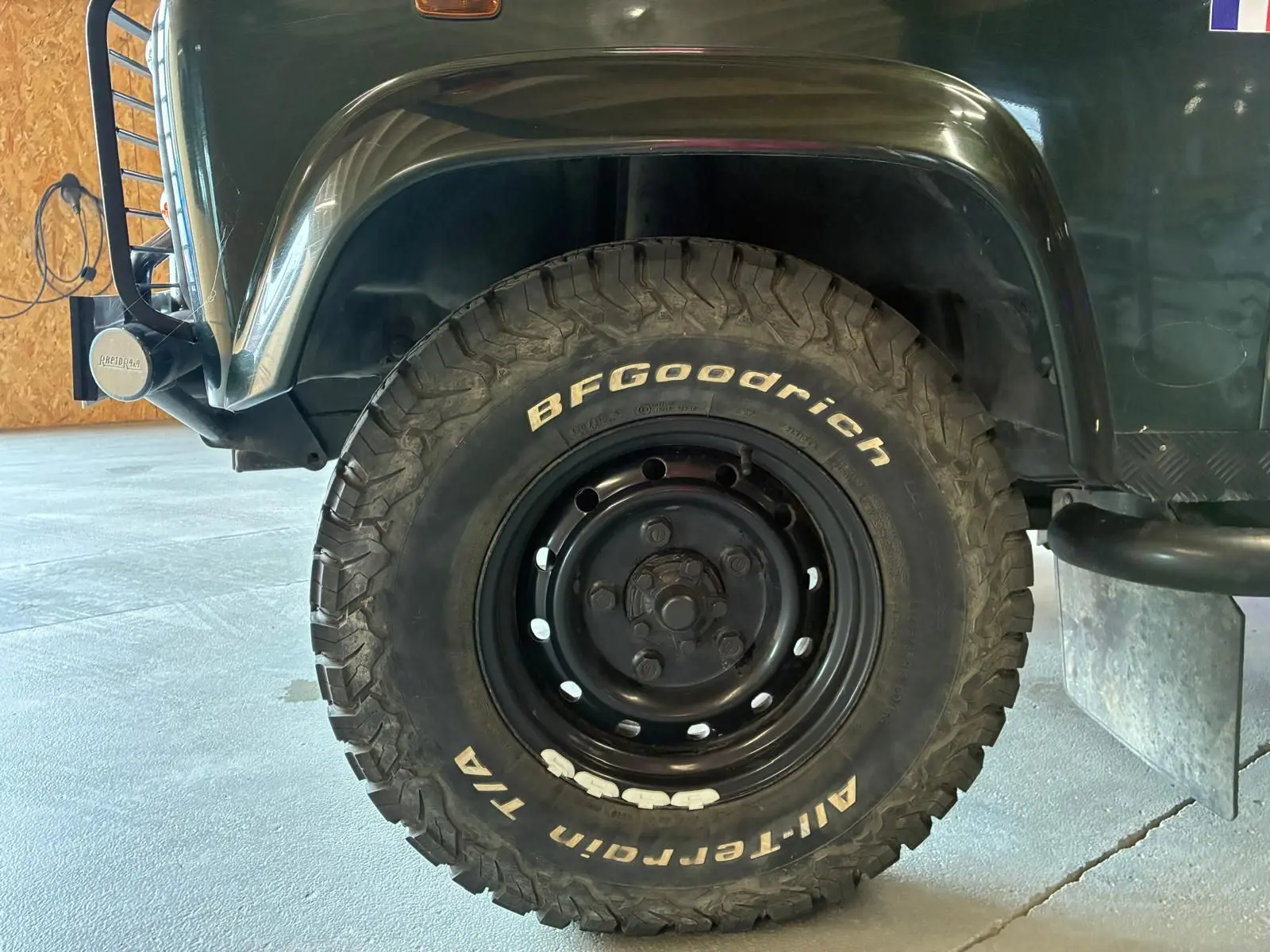 Gros plan sur la roue avant droite d’un Land Rover Defender 110 vert 2005 avec pneu BFGoodrich tout-terrain.