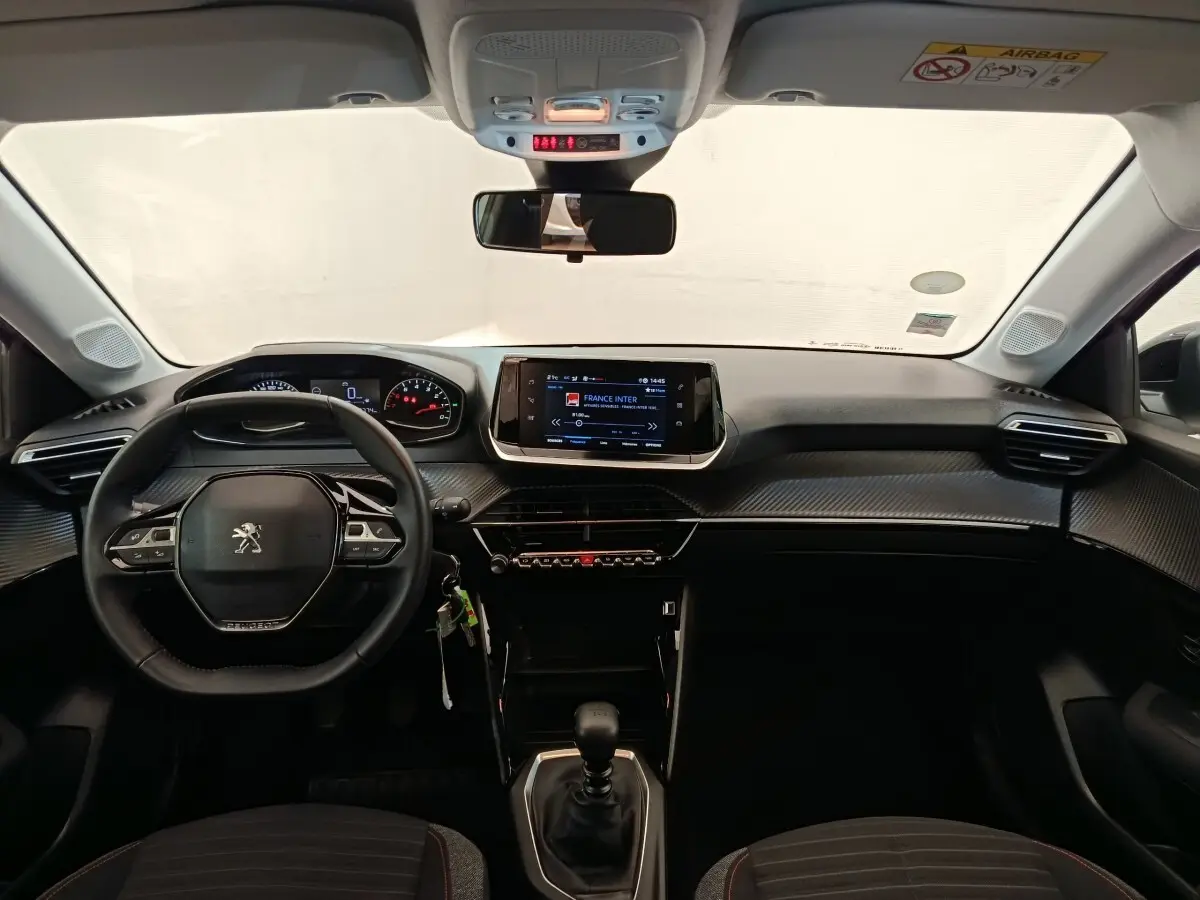 Vue intérieure avant de la Peugeot 208 BlueHDi 100 S&S Active 2022, volant cuir multifonctions et écran tactile central.