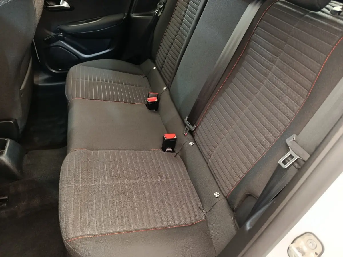 Vue intérieure côté droit sur la banquette arrière noire avec surpiqûres rouges de la Peugeot 208 blanche 2022.