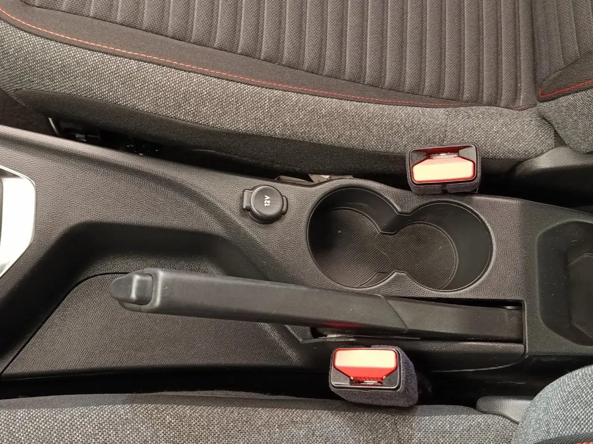 Vue rapprochée de la console centrale de la Peugeot 208 blanche, avec frein à main manuel et porte-gobelets noirs.