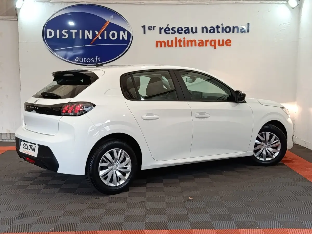Peugeot 208 blanche vue de profil droit en intérieur, avec feux arrière LED et jantes alliage.