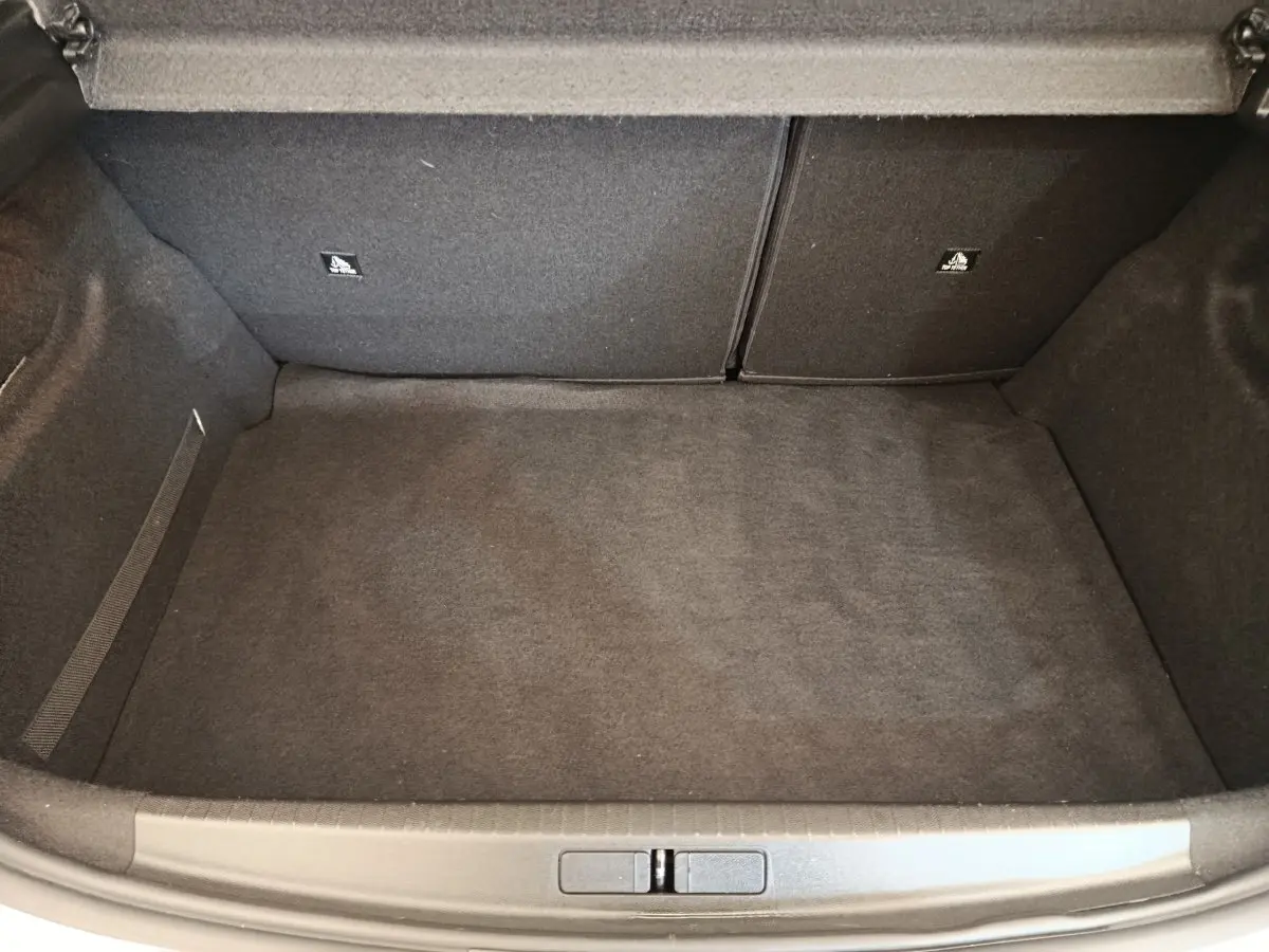 Coffre vide vu de face d'une Peugeot 208 blanche BlueHDi 100 S&S Active, intérieur en moquette grise.