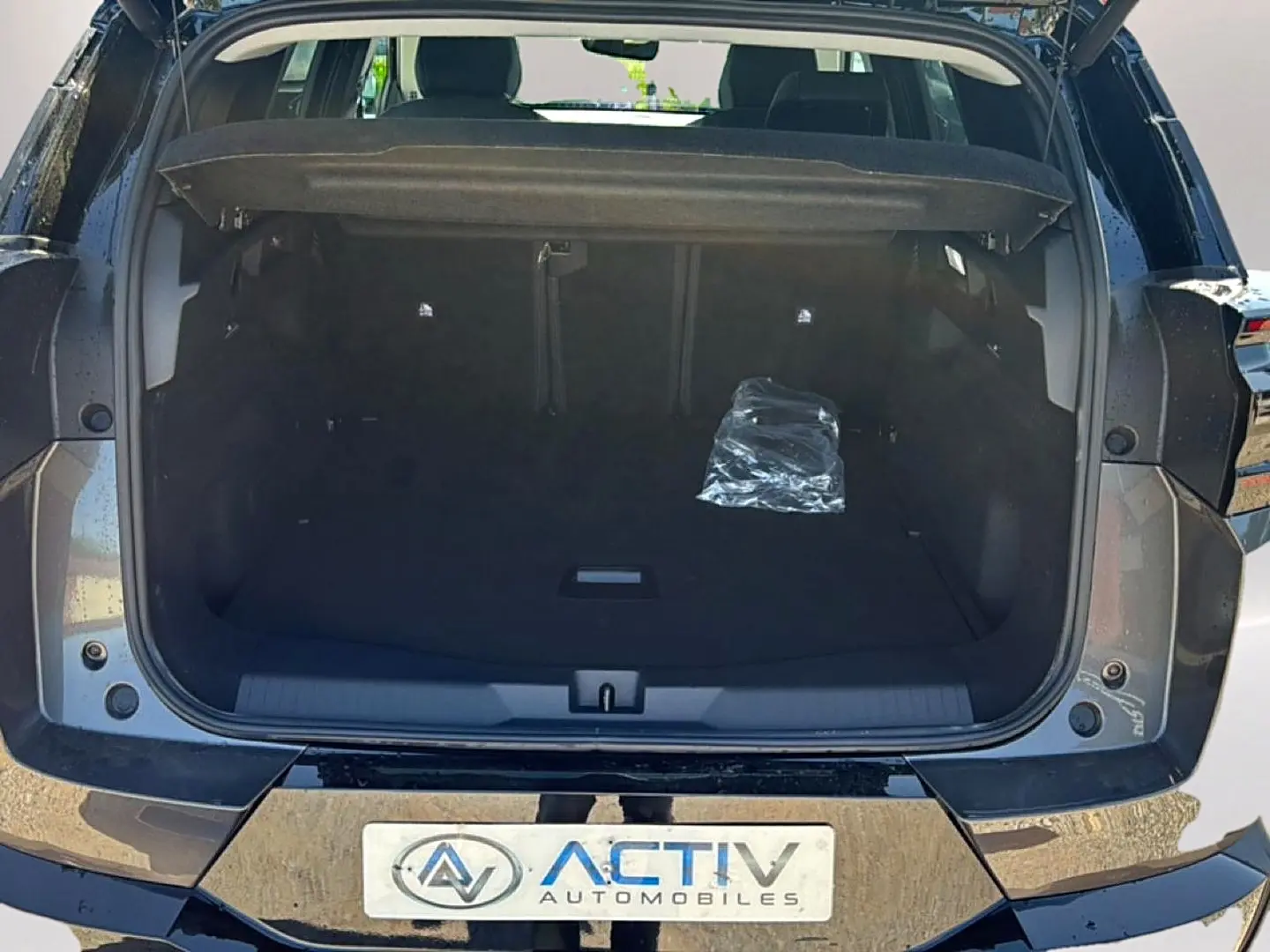 Coffre ouvert vu de l'arrière du Citroën C5 Aircross gris platinium avec hayon électrique et plancher de coffre mobile.