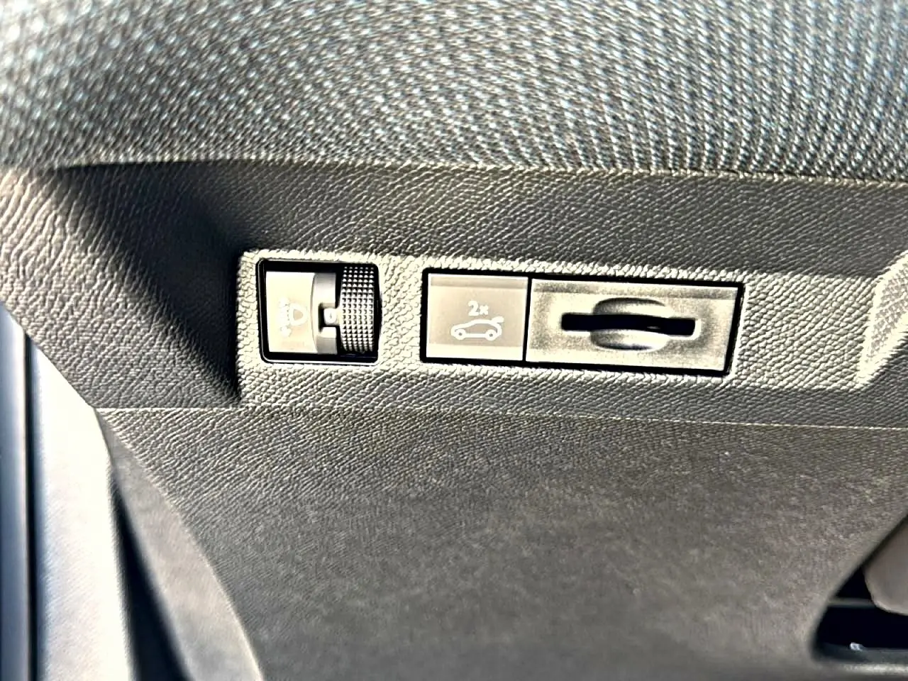 Gros plan sur les commandes d'ouverture du coffre et réglage des phares dans l'habitacle du Citroën C5 Aircross gris platinium.