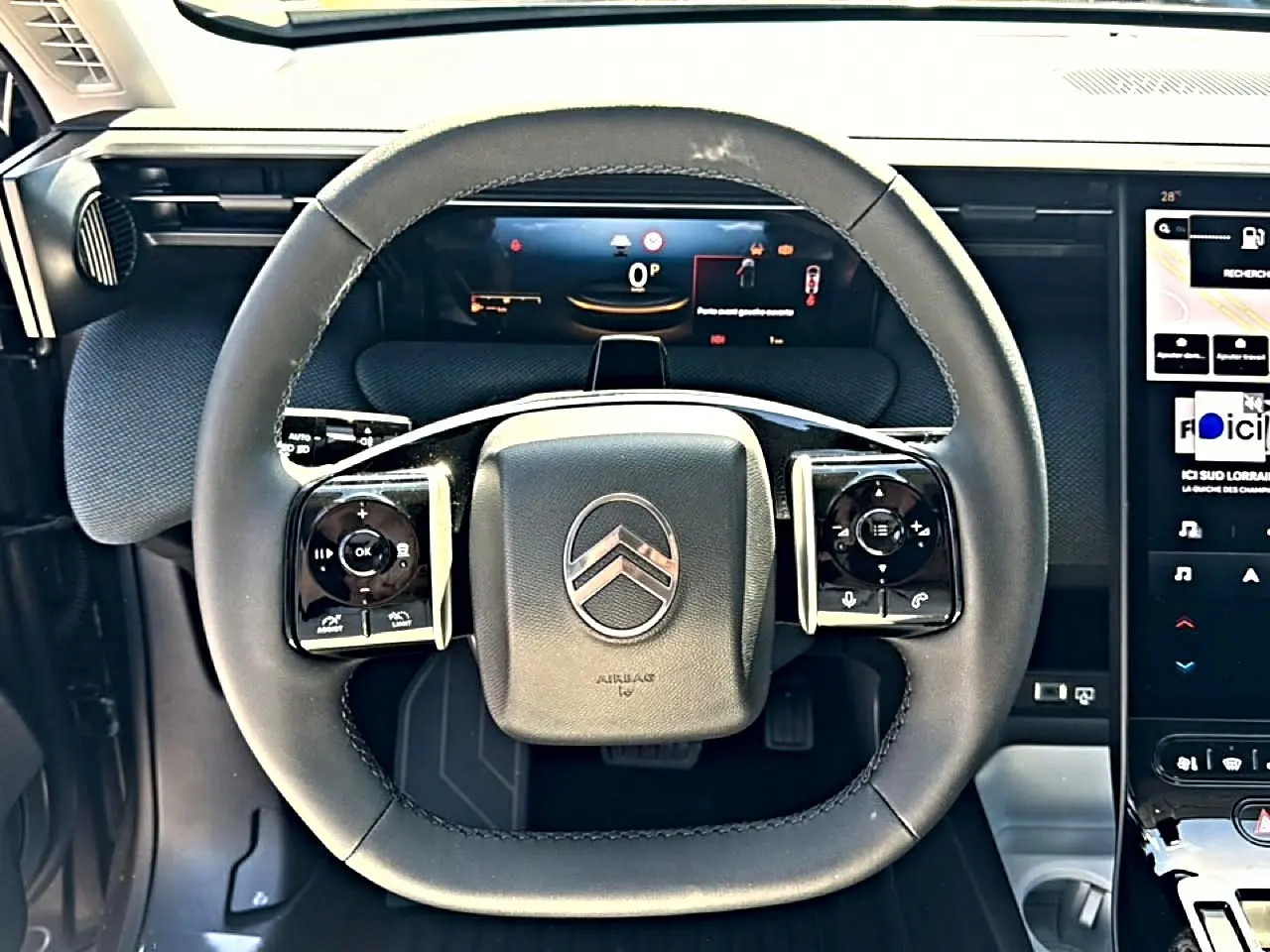 Vue rapprochée du volant multifonction noir du Citroën C5 Aircross 2026 avec tableau de bord numérique en arrière-plan.