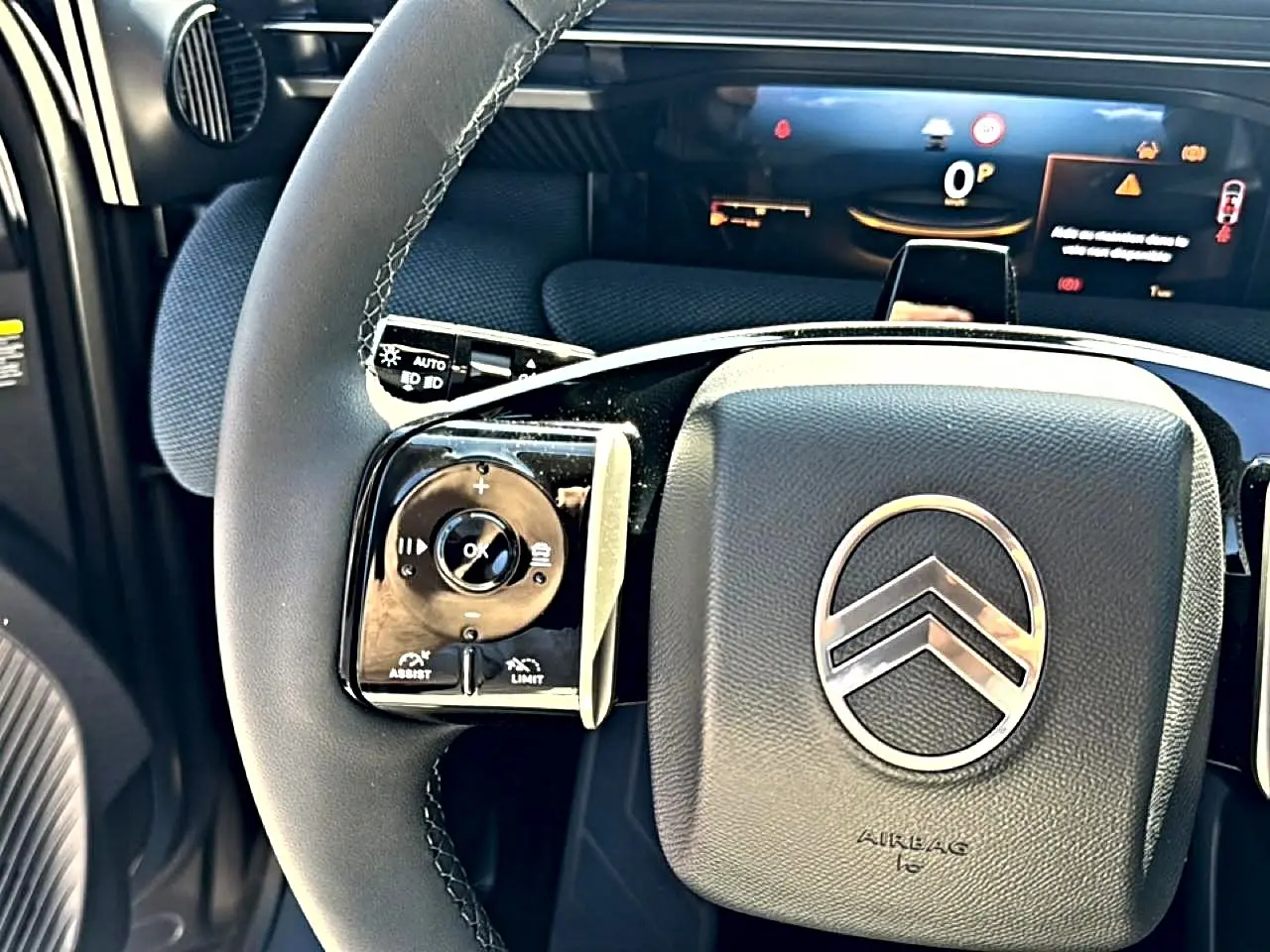 Gros plan sur le volant multifonction noir du Citroën C5 Aircross 2026 avec logo chromé et tableau de bord numérique en arrière-plan.