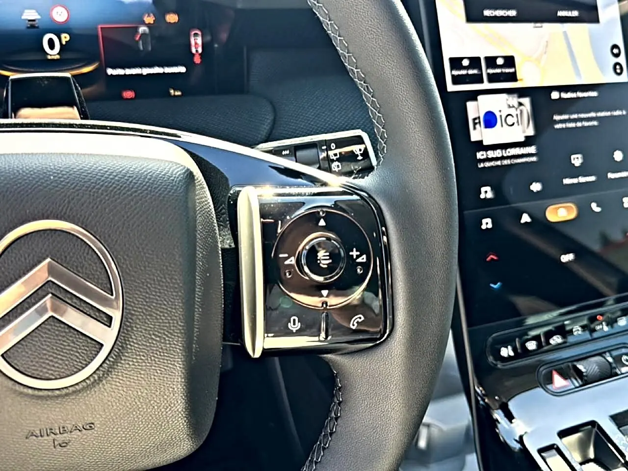 Gros plan sur le volant cuir noir et les commandes multifonctions du Citroën C5 Aircross 2026, écran tactile visible.