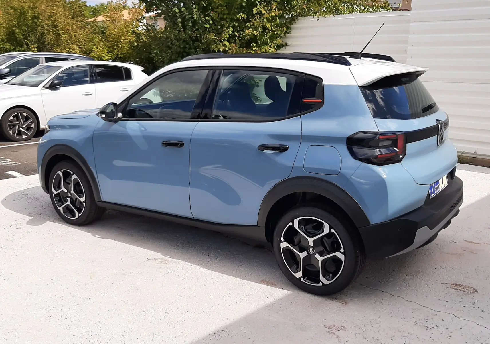 Vue 3/4 arrière droite d'une Citroën C3 bleu Monte Carlo avec toit blanc et jantes noires au design moderne.