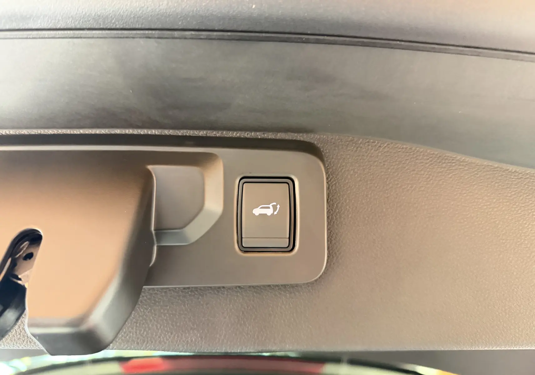 Bouton d'ouverture électrique du hayon sur la garniture intérieure d'un Renault Austral E-Tech 200 Esprit Alpine.