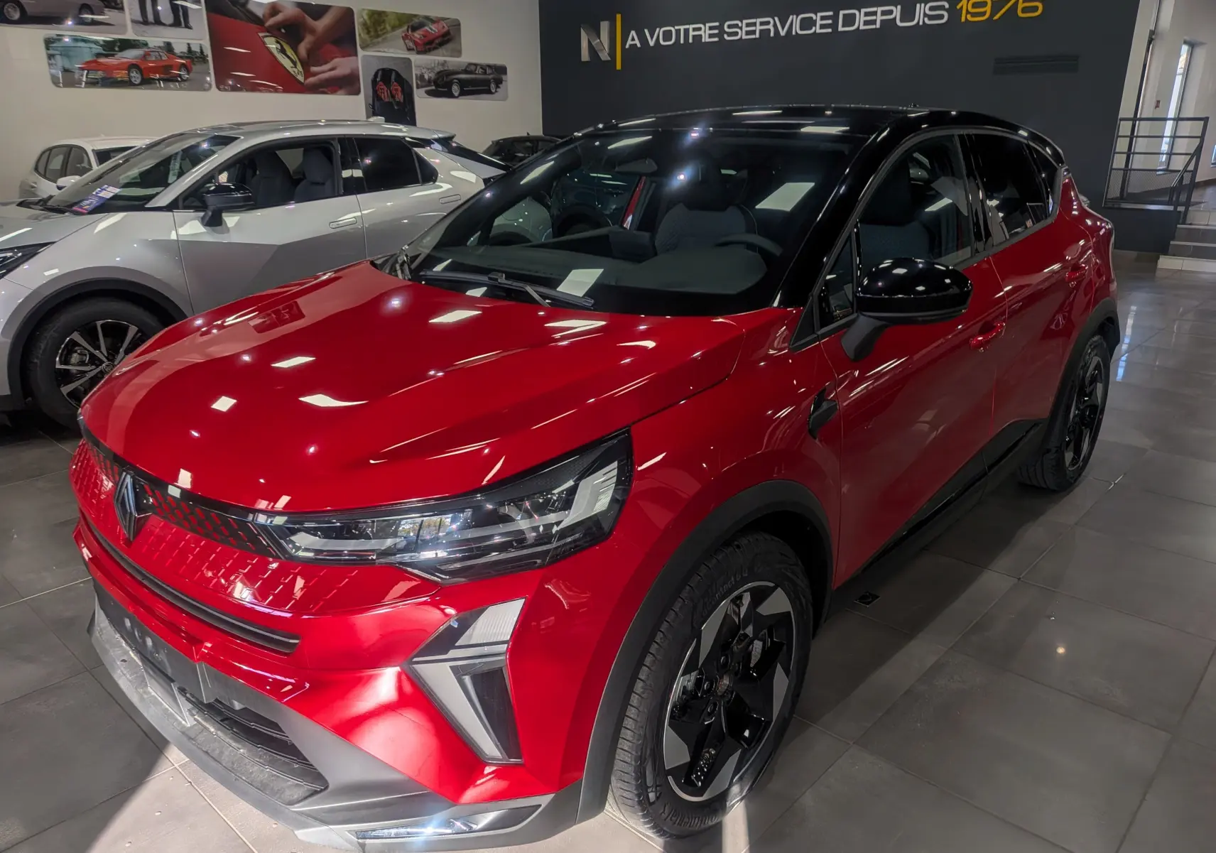 Renault Captur E-TECH rouge flamme avec toit noir, vue 3/4 avant droit dans un showroom moderne.