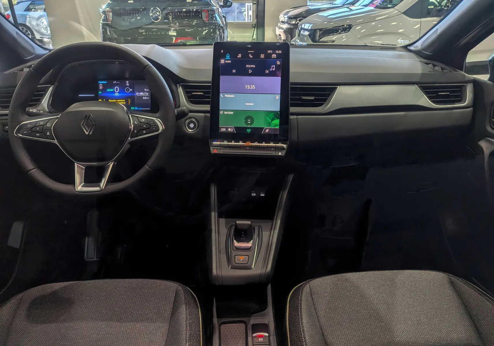 Tableau de bord et volant du Renault Captur E-TECH 2025 vus de face, avec écran tactile central vertical et finitions noires.