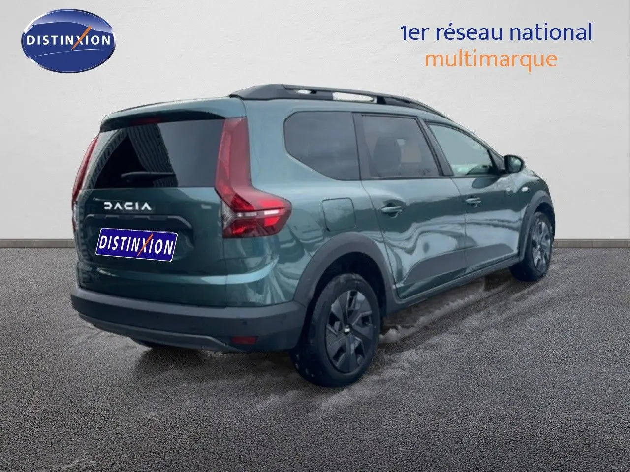 Vue 3/4 arrière droite d'un Dacia Jogger 2025 vert cèdre métallisé avec vitres teintées et barres de toit.