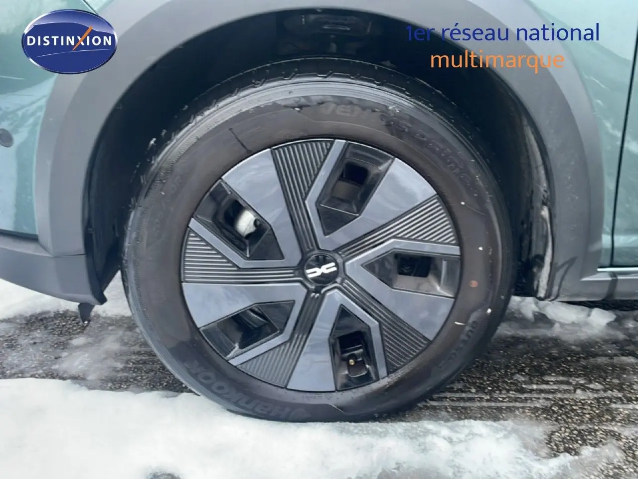 Gros plan sur la roue avant droite du Dacia Jogger vert cèdre métal avec jante noire au design géométrique.