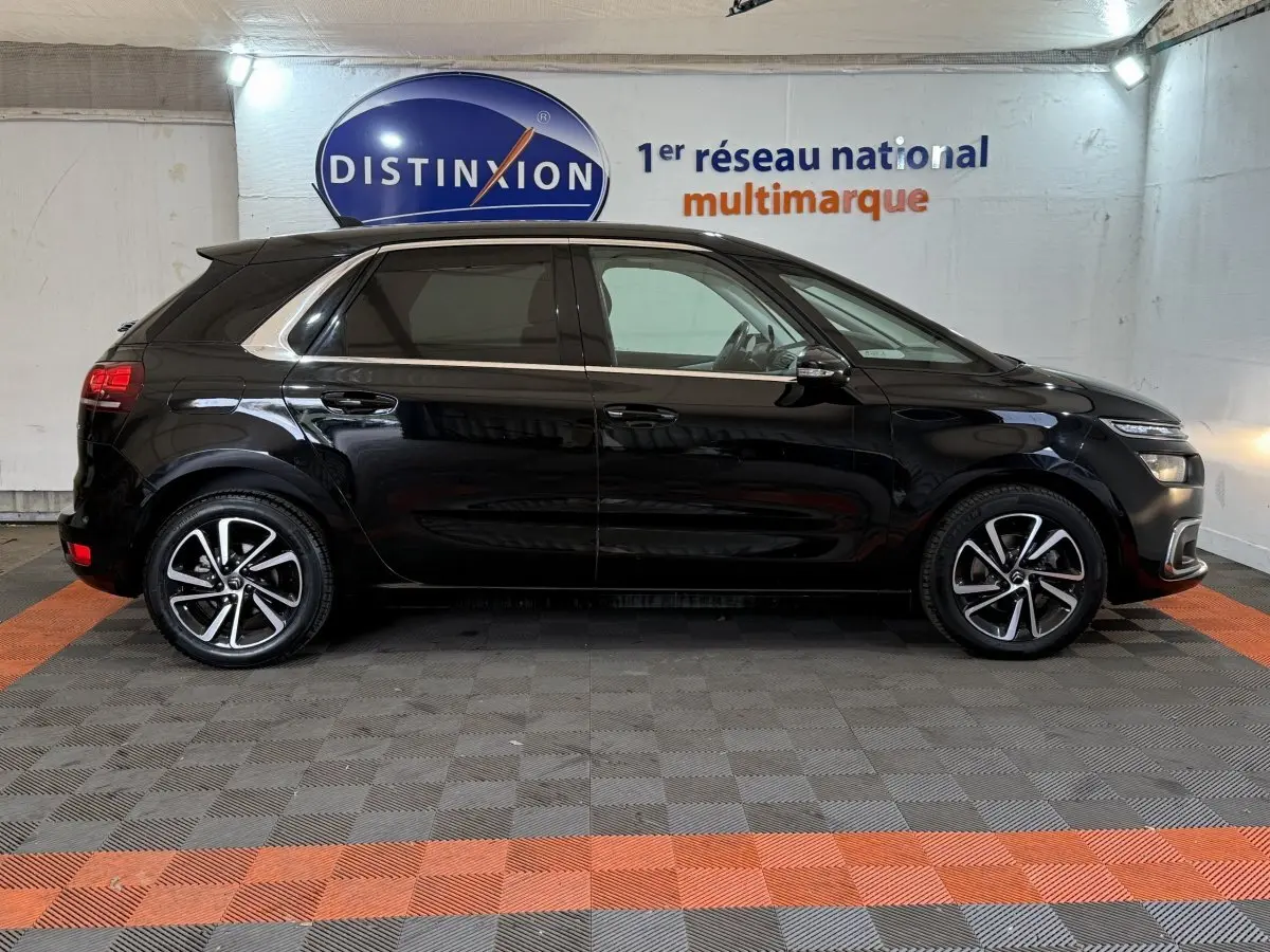 Profil droit d'une Citroën C4 Spacetourer noire 2020 avec jantes alliage et vitres teintées en intérieur showroom.