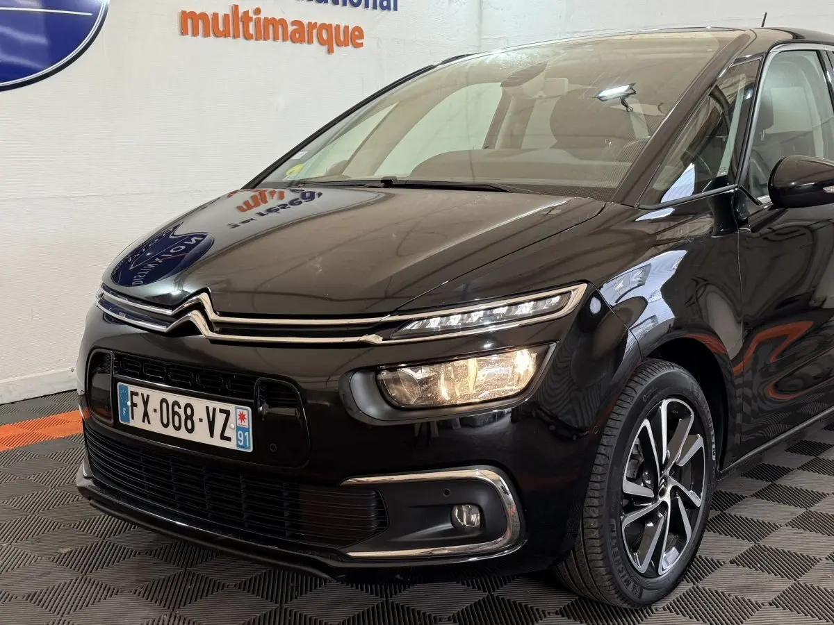 Vue 3/4 avant droite d'une Citroën C4 Spacetourer noire avec phares allumés et jantes alliage distinctives.