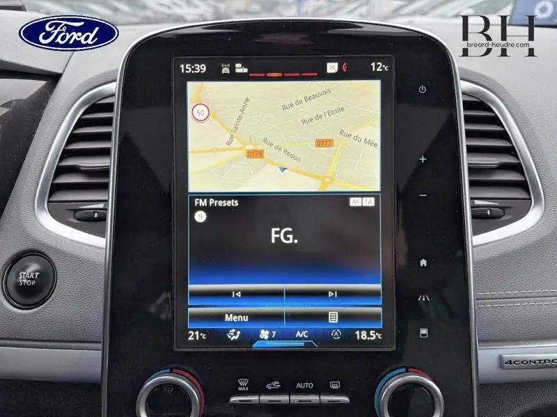 Écran tactile central du tableau de bord d’un Renault Espace blanc Glacier, affichant la navigation GPS et la radio FM.