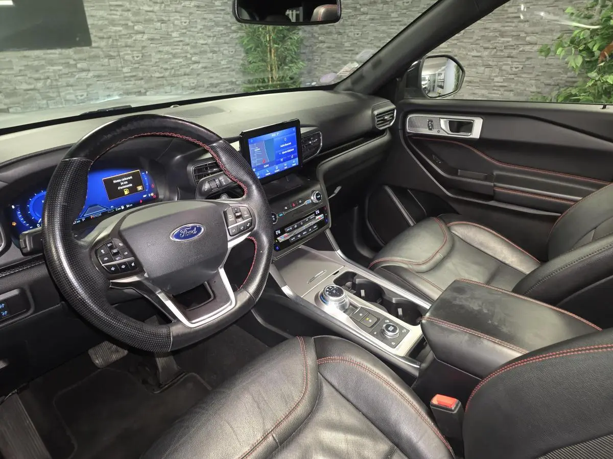 Vue intérieure côté conducteur du Ford Explorer 2020, sièges cuir noirs avec surpiqûres rouges et écran tactile central.