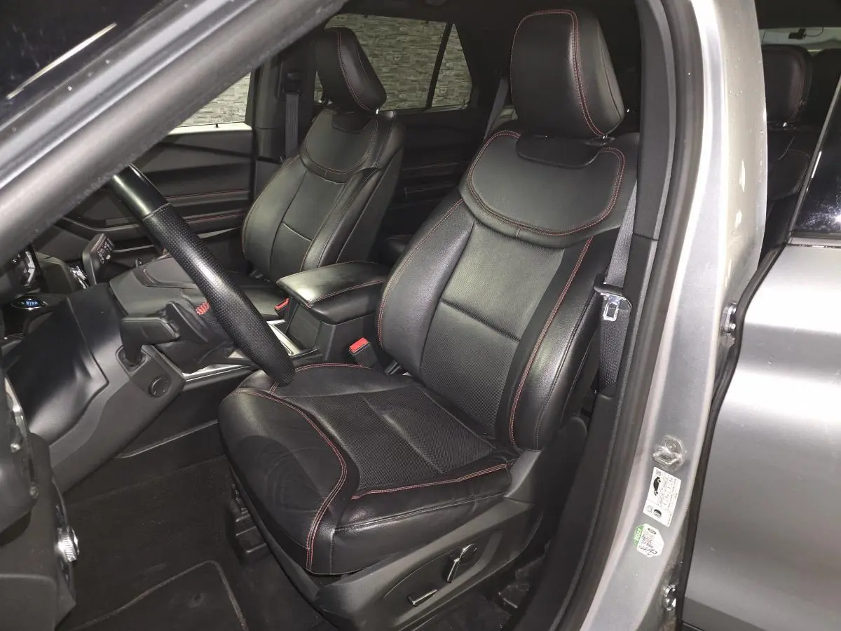 Vue intérieure côté conducteur du Ford Explorer gris, sièges cuir noirs avec surpiqûres rouges et volant sport ST-Line.