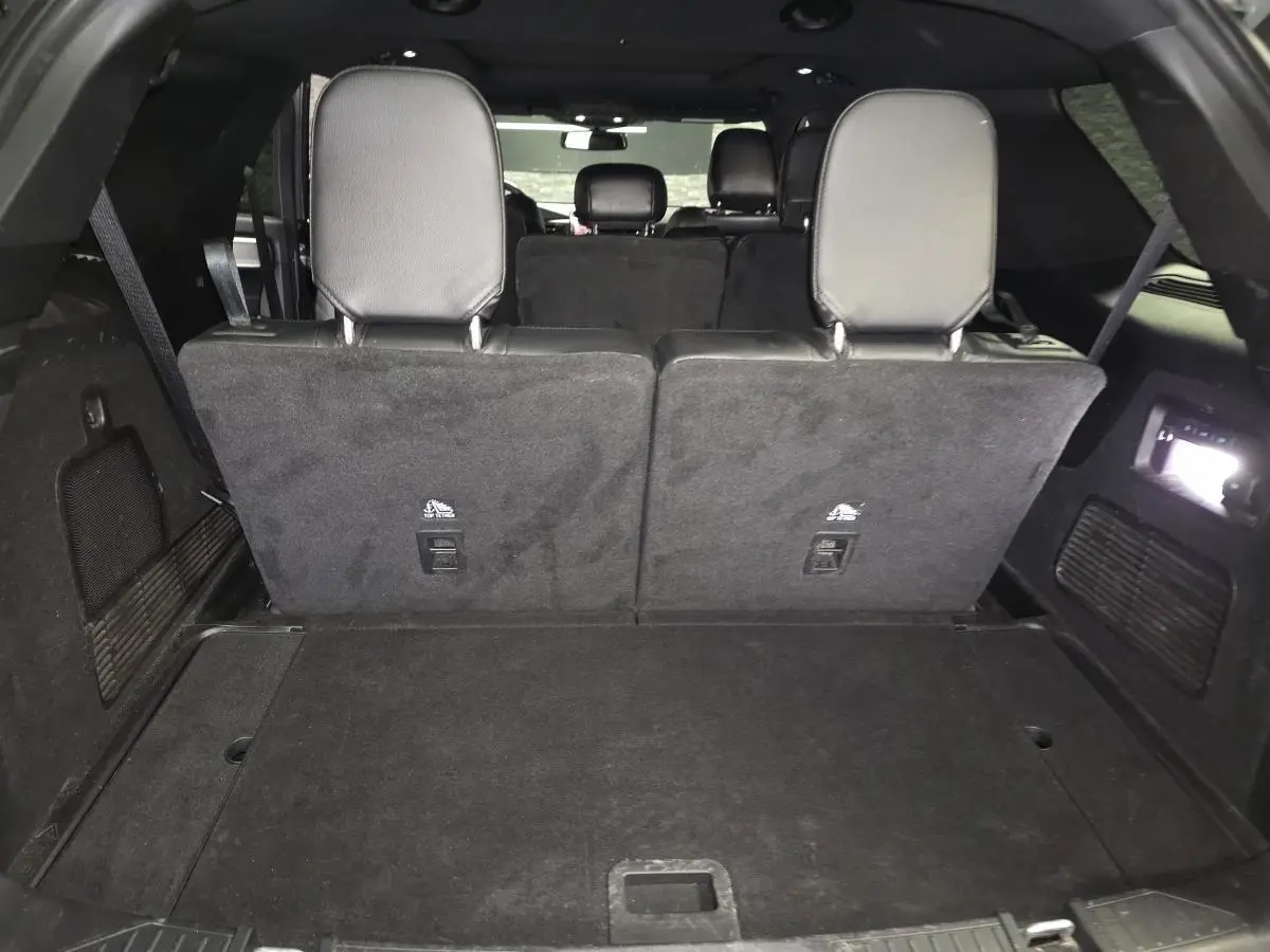 Vue arrière du coffre spacieux du Ford Explorer gris avec banquette arrière relevée et éclairage intérieur actif.
