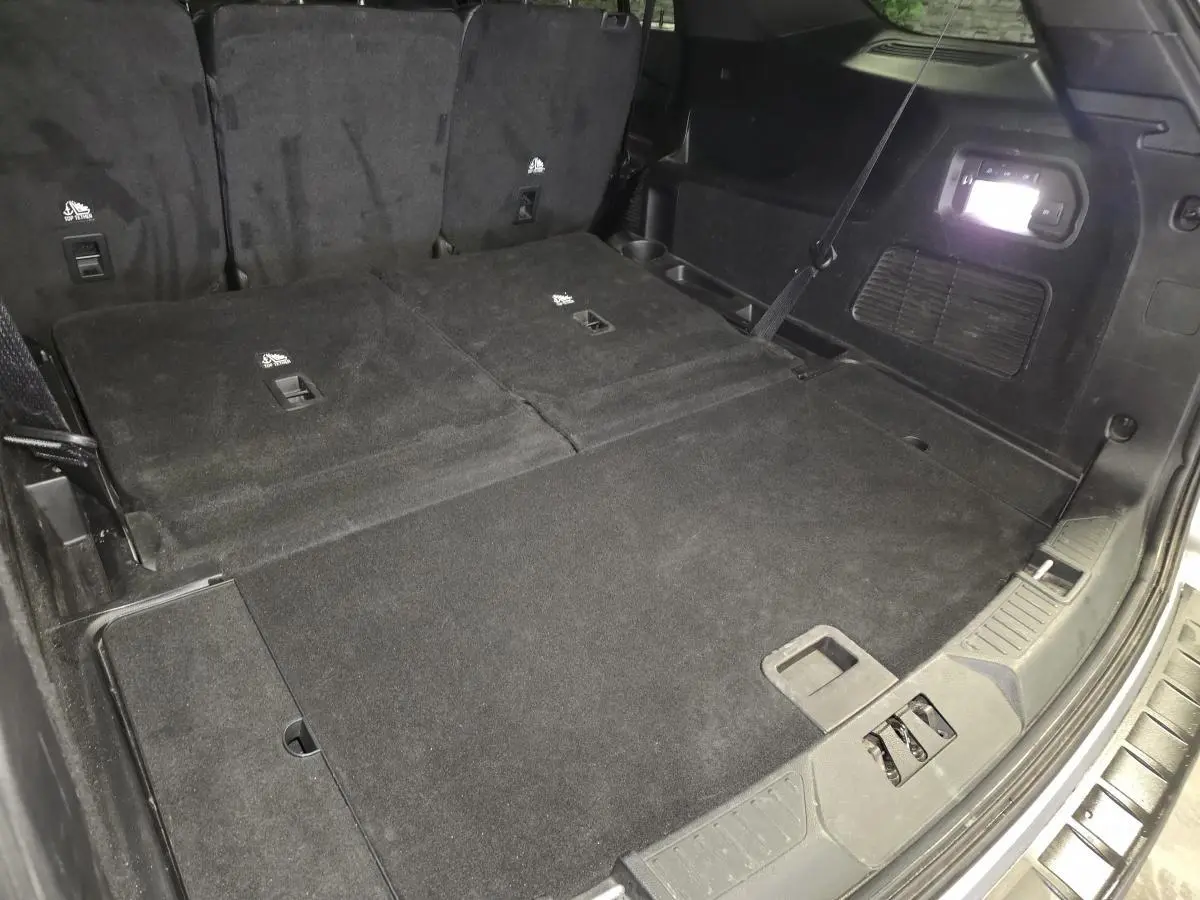 Vue du coffre arrière avec banquette rabattue du Ford Explorer gris, mettant en valeur l'espace de chargement plat.