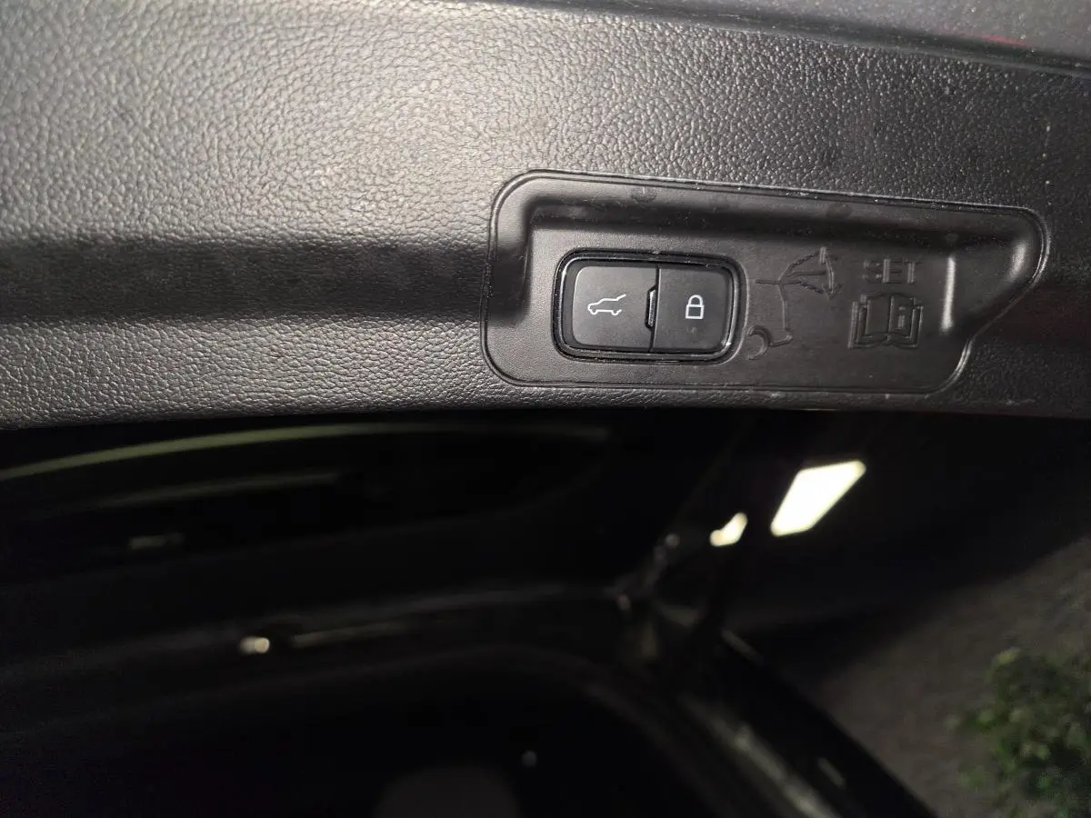 Bouton d'ouverture et de verrouillage électrique du coffre sur le hayon intérieur du Ford Explorer gris.