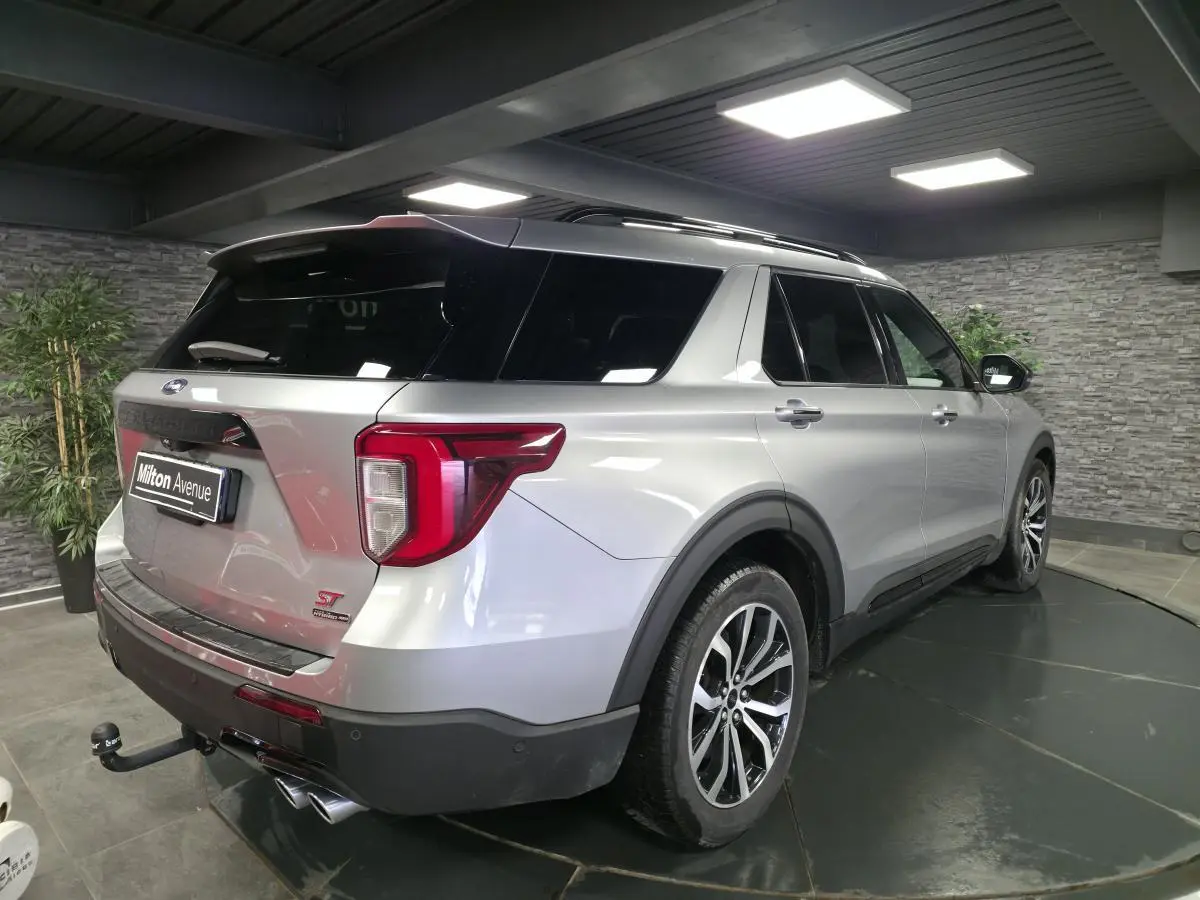Vue 3/4 arrière droite du Ford Explorer gris métallisé avec attelage et jantes alliage noires brillantes.