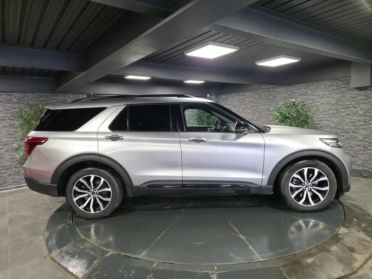 Ford Explorer gris métallisé vu de profil côté gauche dans un garage, avec jantes alliage noires et toit noir.