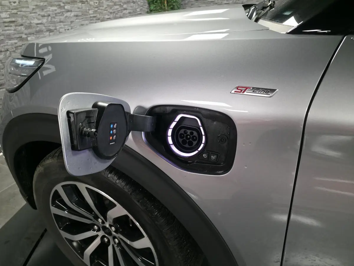 Prise de recharge ouverte côté avant gauche du Ford Explorer gris métallisé ST-Line avec jante alliage noire et badge ST-Line.