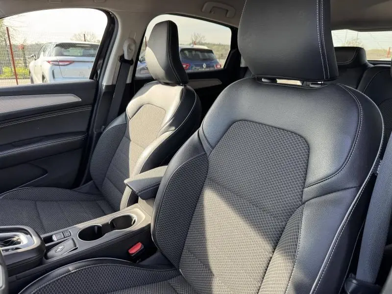 Vue intérieure rapprochée des sièges avant en tissu noir et cuir avec surpiqûres blanches du Renault Arkana 2023.