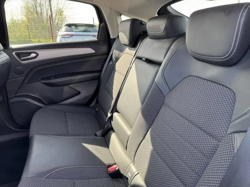 Vue intérieure du siège arrière droit du Renault Arkana 2023, tissu noir avec surpiqûres blanches et accoudoir central.