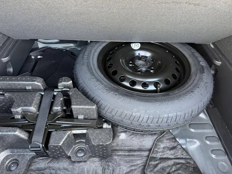 Vue rapprochée sous le coffre du Renault Arkana 2023 noir métal montrant la roue de secours et le cric.