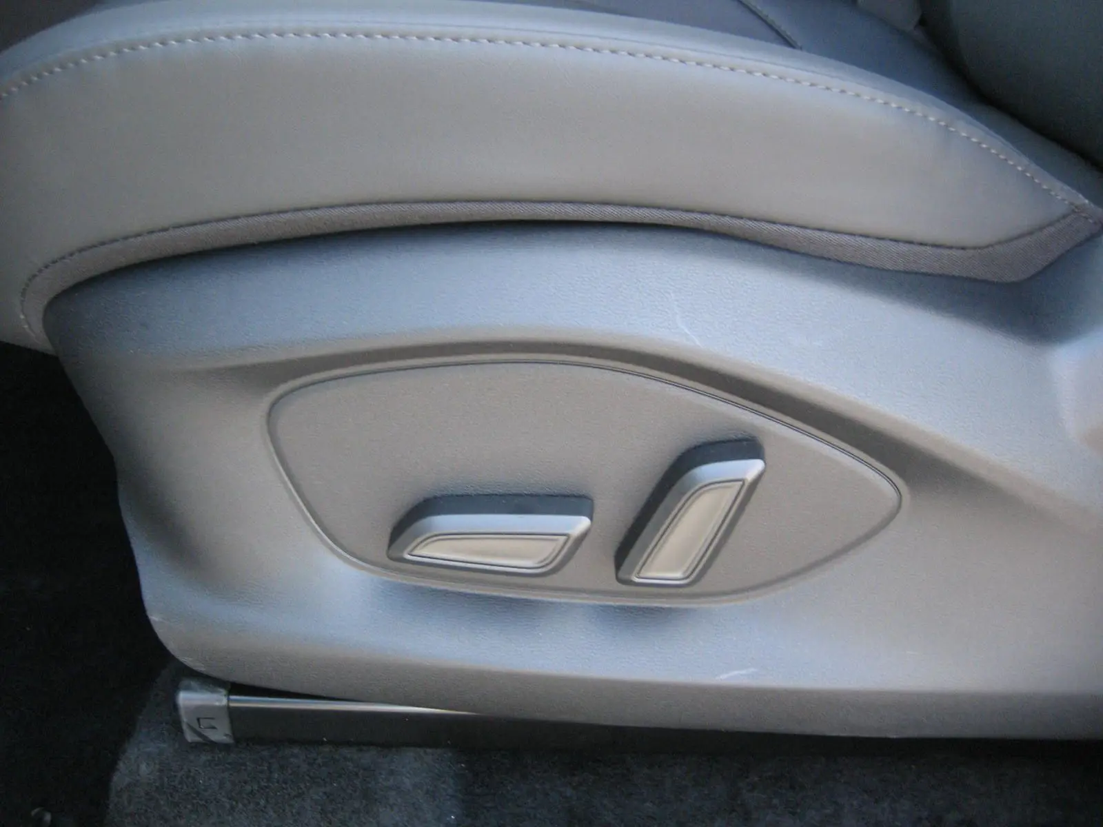Détail des commandes de réglage électrique du siège en cuir noir du MG ZS 1.5 HYBRID+197 LUXURY blanc, vue côté gauche.