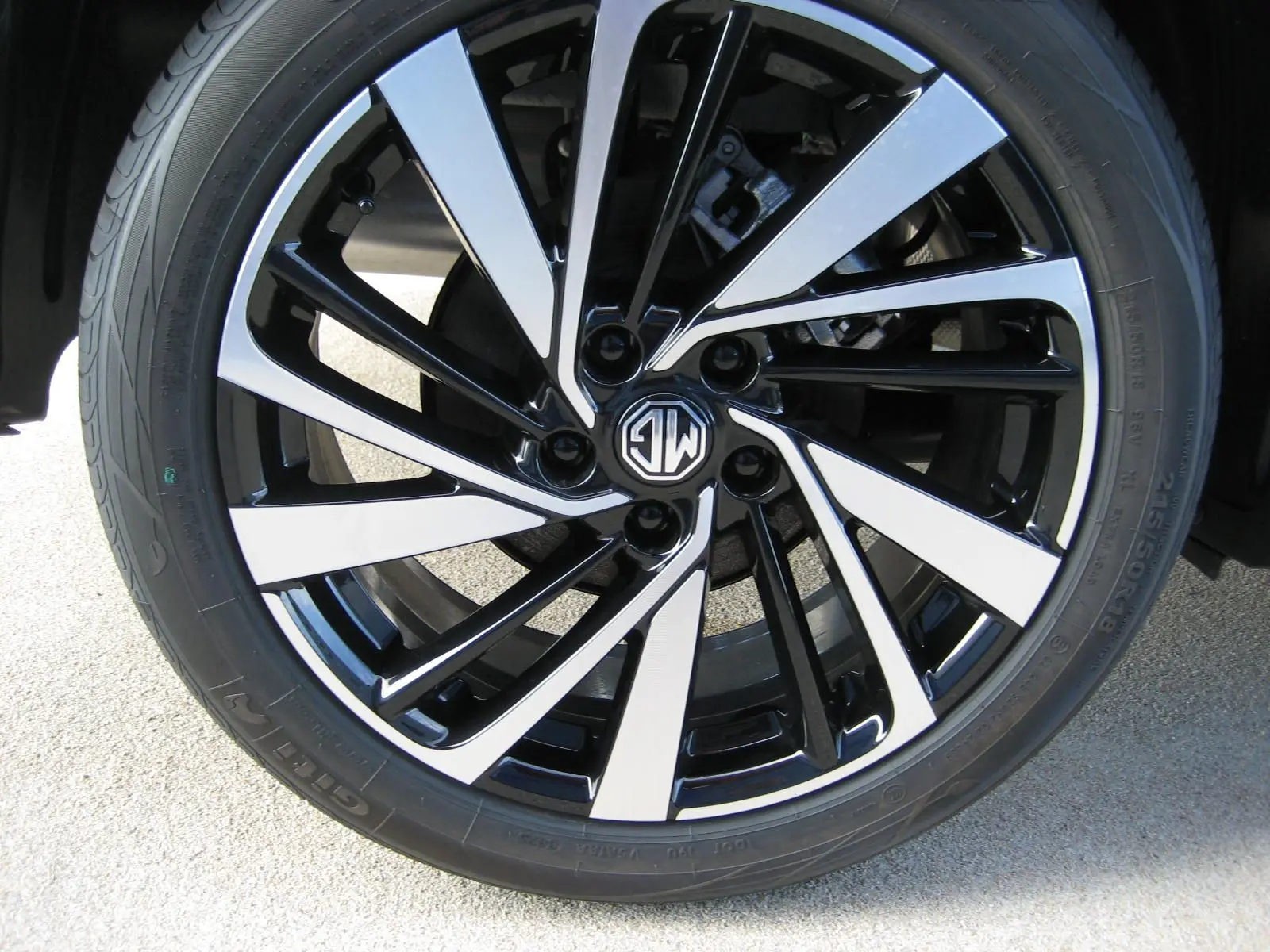 Gros plan sur la jante noire et argentée du MG ZS blanc, mettant en valeur le logo MG au centre.