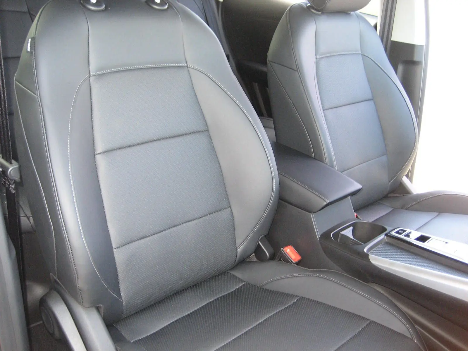 Gros plan sur les sièges avant en cuir noir du MG ZS 1.5 HYBRID+197 LUXURY, avec console centrale visible.