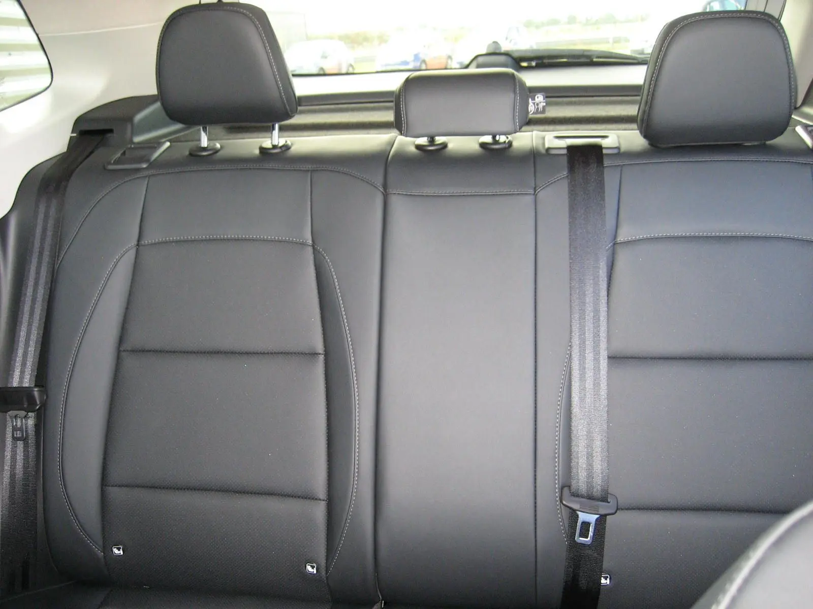 Vue rapprochée des sièges arrière en cuir noir du MG ZS 1.5 HYBRID+197 LUXURY 2026, avec appuie-têtes et ceinture de sécurité.