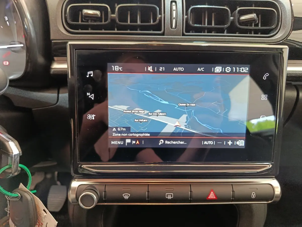 Vue rapprochée de l’écran tactile central du système de navigation 3D dans l’habitacle noir d’une Citroën C3 blanche.