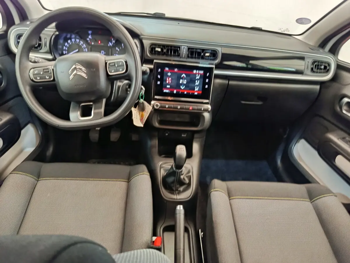 Vue intérieure avant de la Citroën C3 blanche 2022, volant multifonctions, écran tactile central et boîte manuelle.