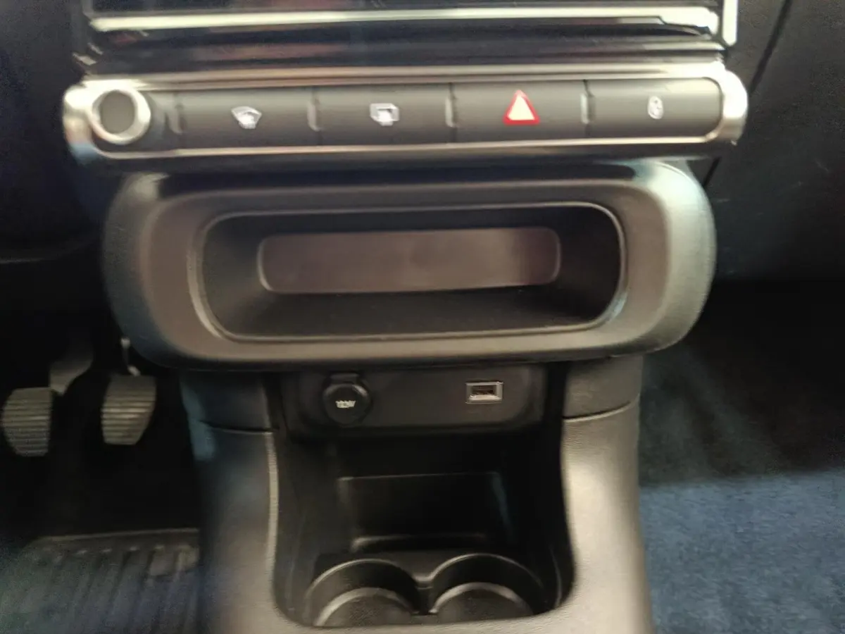 Gros plan sur la console centrale noire de la Citroën C3 2022, avec prise 12V et port USB visibles.