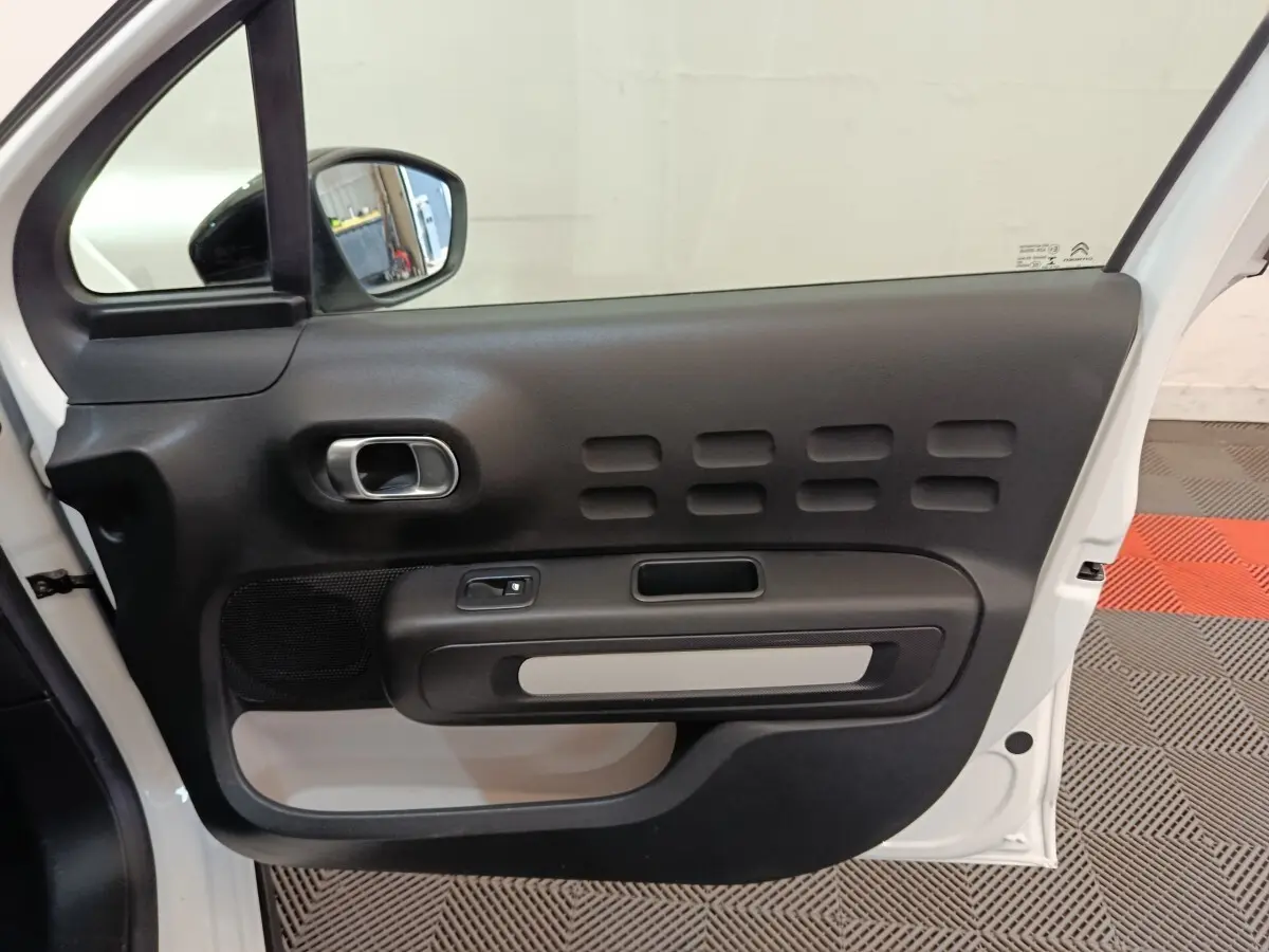 Vue intérieure de la porte avant gauche blanche d'une Citroën C3 avec poignée argentée et haut-parleur intégré.