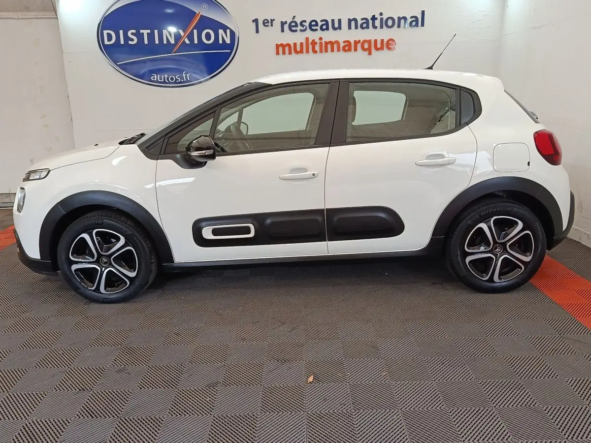 Profil droit d'une Citroën C3 blanche de 2022 avec protections latérales noires et jantes alliage bicolores.