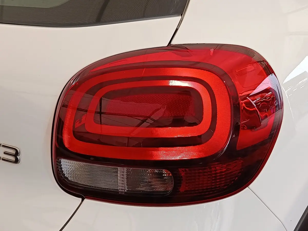 Gros plan sur le feu arrière droit rouge d'une Citroën C3 blanche, mettant en valeur son design arrondi et moderne.